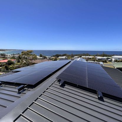 A Row Of Solar Panels On Top Of A Building With A City In The Background — Solarblu Pty Ltd In Wollongong, NSW