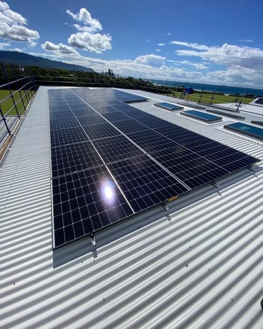 Two Men Are Working On A Solar Panel On Top Of A Building — Solarblu Pty Ltd In Woonona, NSW