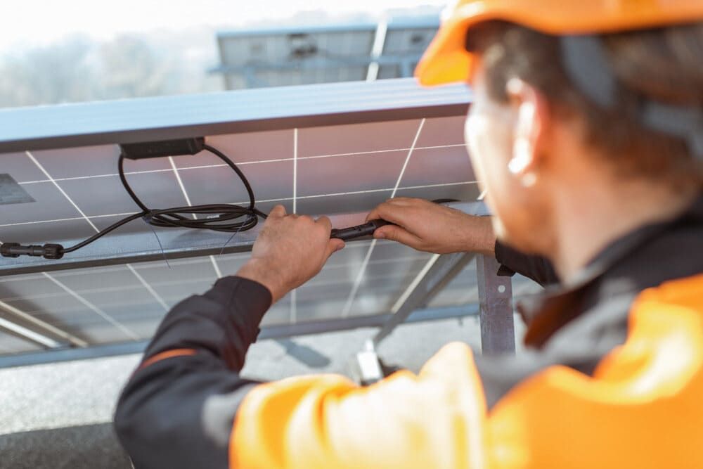 A Man Is Installing A Solar Panel On A Roof — Solarblu Pty Ltd In Dapto, NSW