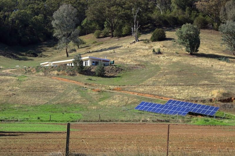 A Row of Solar Panels Are Sitting in a Field Next to a House — Solarblu Pty Ltd in Kangaroo Valley, NSW
