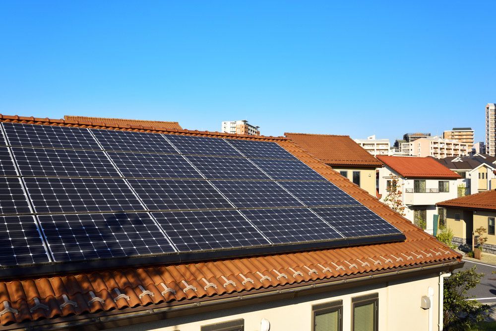 Rooftop Solar Panels on a House Under a Clear Blue Sky — Solarblu Pty Ltd In Woonona, NSW