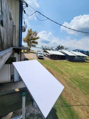 White awning outside a building overlooking a grassy yard, parked car, and long barn-like structures under a blue sky