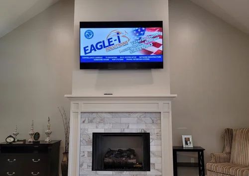 Living room with wall-mounted TV above a white fireplace and black-framed mirror.