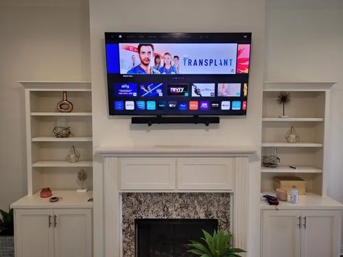 Living room with wall-mounted TV above fireplace and built-in white shelves on both sides