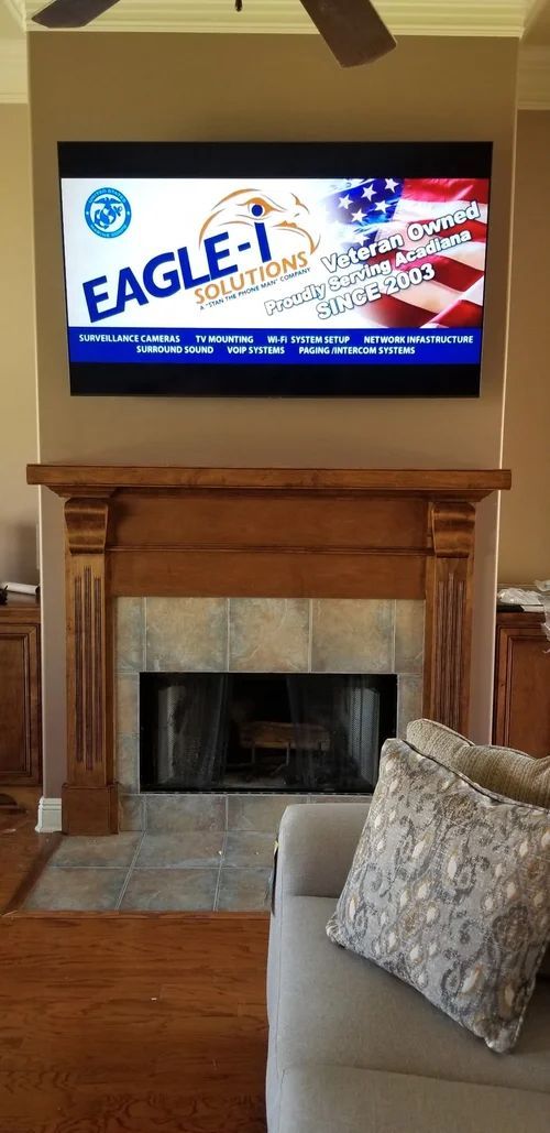 Living room with a TV showing an Eagle-1 ad above a wooden fireplace mantel
