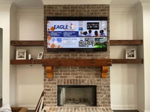 Living room fireplace with a wall-mounted TV displaying an Eagle renovation website