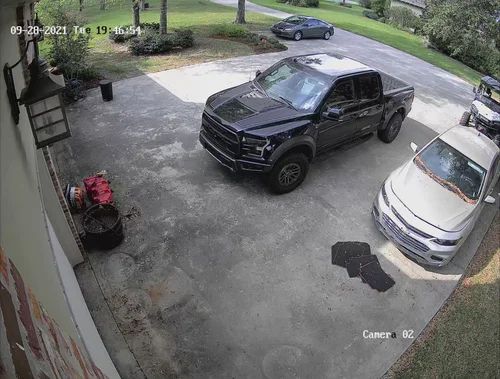Driveway with a black pickup truck, white SUV, and a planter by the garage entrance.
