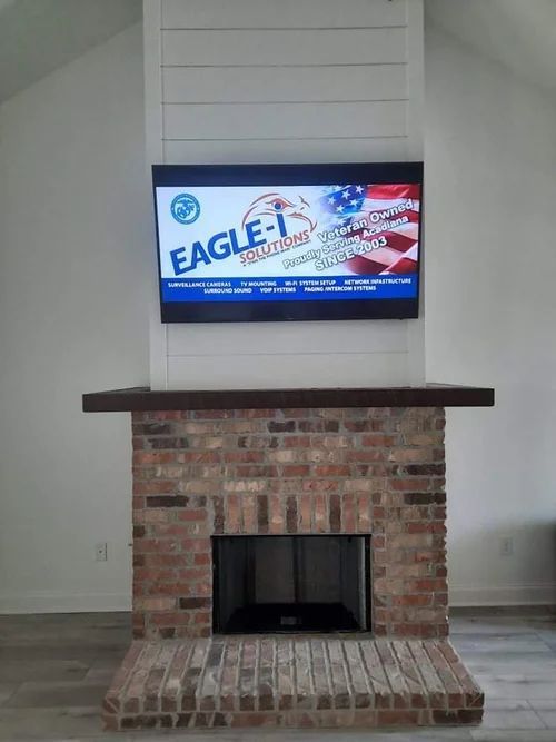 Brick fireplace with a mounted TV displaying an Eagle graphic in a white-walled room