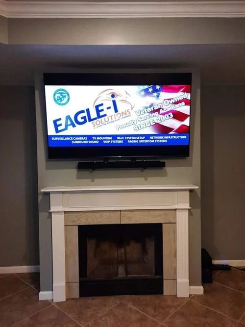 TV above a white fireplace in a living room, displaying a colorful Eagle-I graphic.