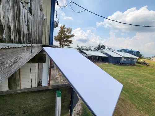 White metal ramp attached to a barn, leading down to a grassy farmyard under a cloudy sky