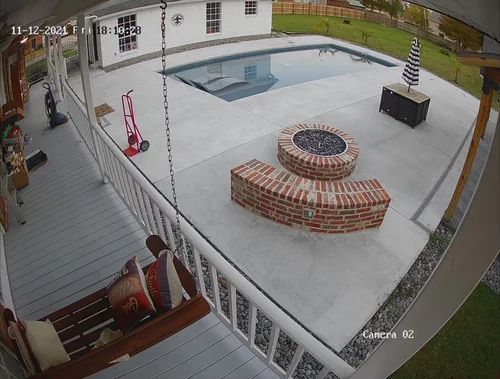 Backyard patio with swimming pool, brick fire pit, grill, and deck chairs seen from above