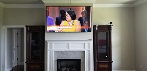 TV mounted above a white fireplace mantel in a living room