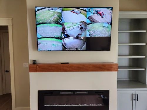 Wall-mounted TV showing multiple security camera feeds above a fireplace in a living room