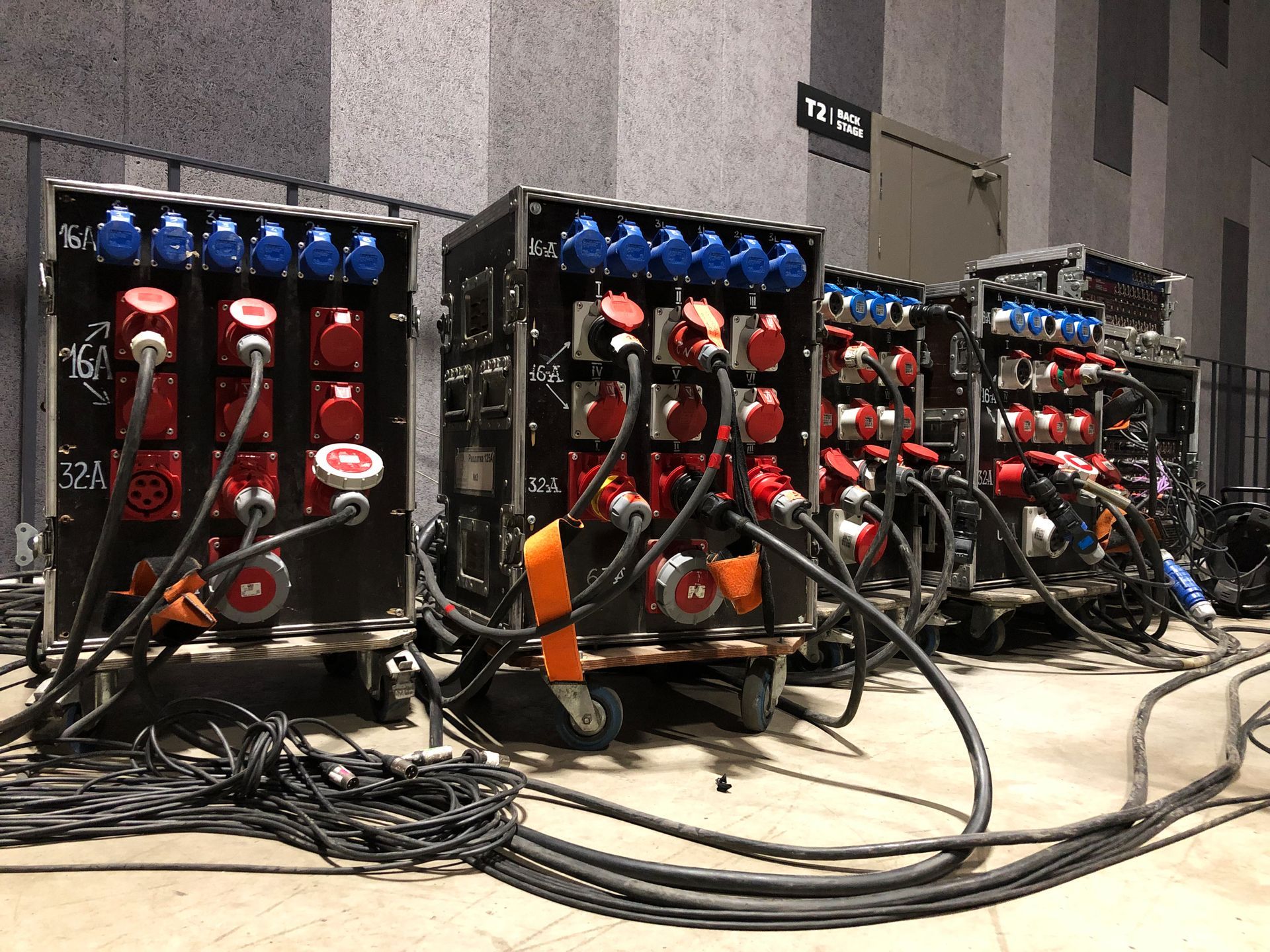 Rows of colorful electrical equipment and tangled cables in a workshop or lab setting