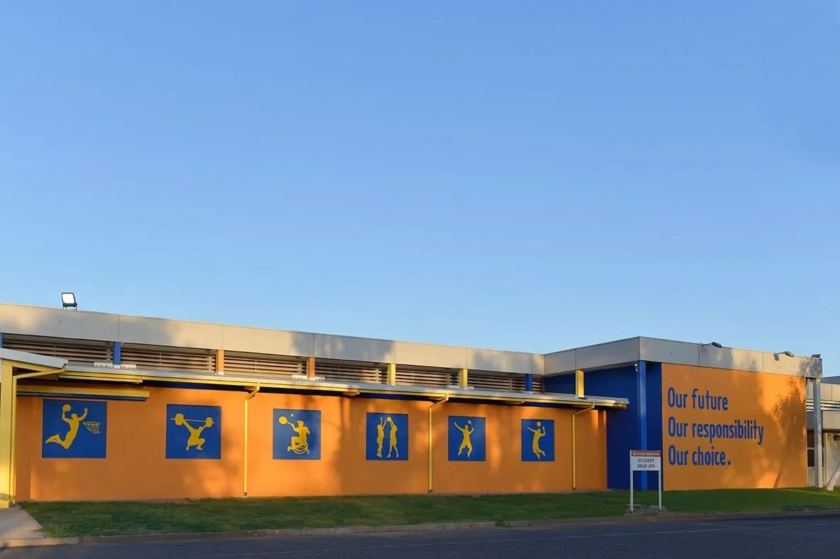 A Yellow and Blue Building With a Sign That Says Do Nothing  — NHM Painting & Projects Pty Ltd in Ciccone, NT