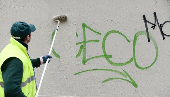 A Man is Painting Graffiti on a Wall With a Roller  — NHM Painting & Projects Pty Ltd in Ciccone, NT