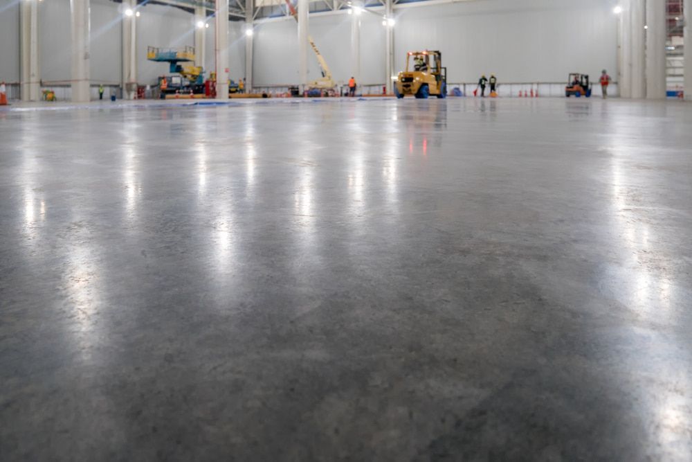 A Large Warehouse With a Shiny Concrete Floor and a Forklift — NHM Painting & Projects in Ciccone, NT