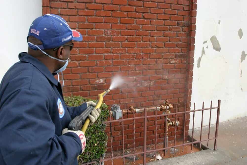 A Man Spraying a Brick Wall With a Hose — NHM Painting & Projects in Ciccone, NT