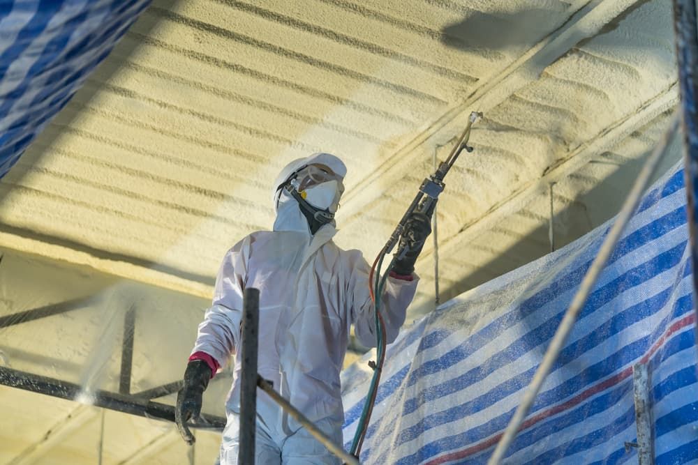 A Man is Spraying Foam on the Ceiling of a Building  — NHM Painting & Projects in Ciccone, NT