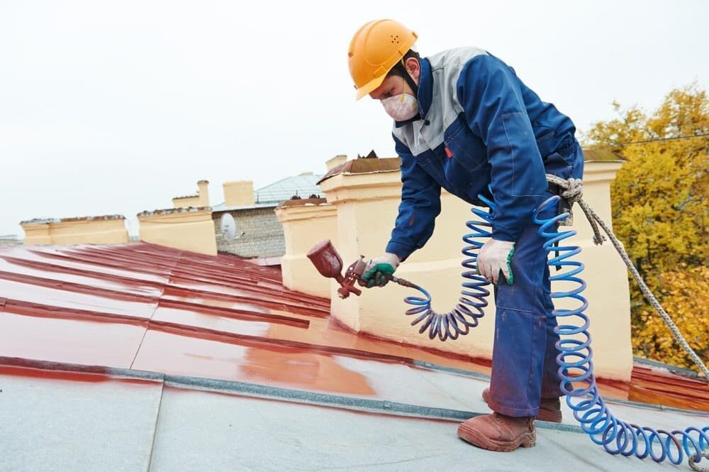 A Man is Spraying Paint on the Roof of a Building  — NHM Painting & Projects in Ciccone, NT