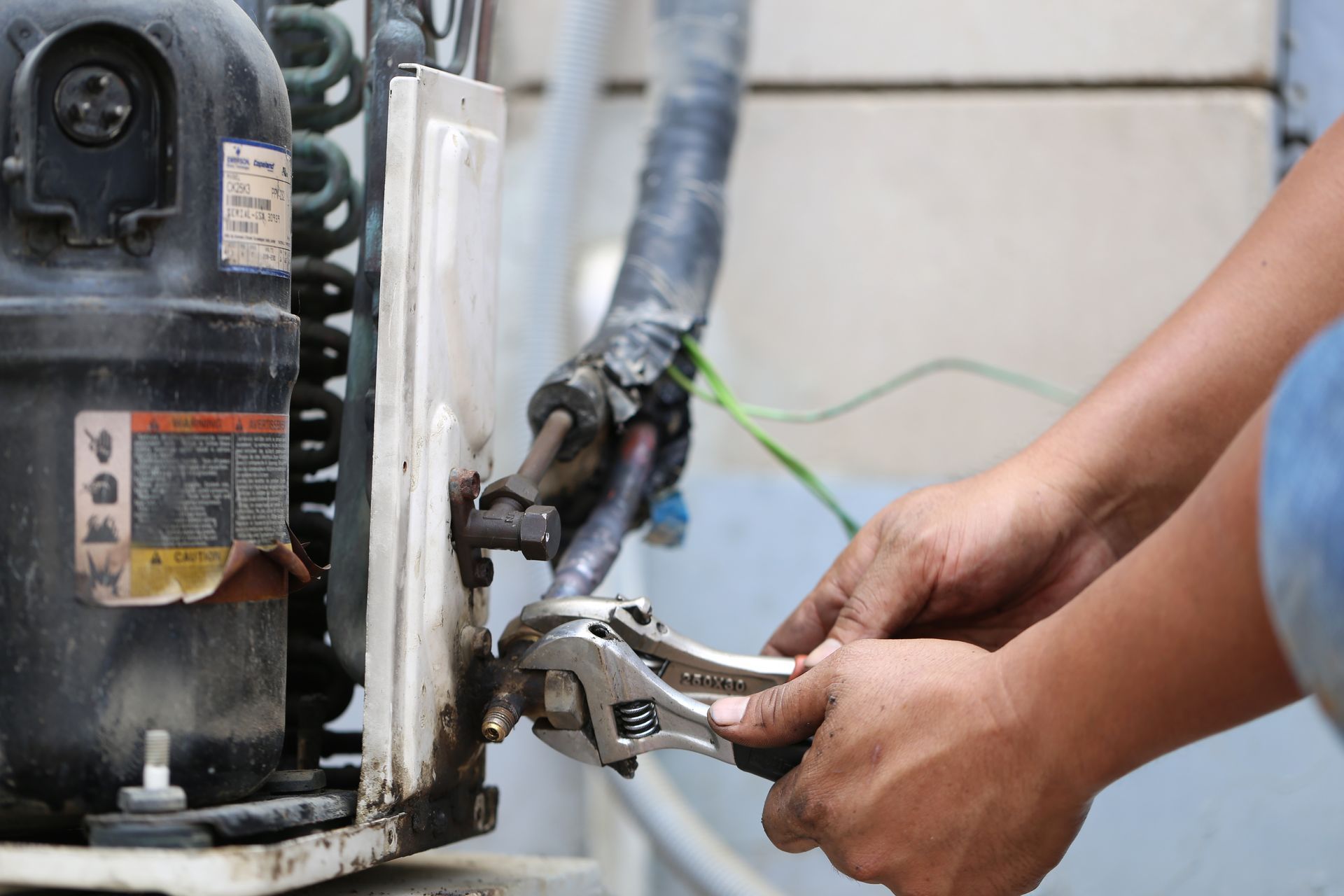 Hands use a wrench to tighten connections on HVAC equipment during indoor furnace maintenance. Hands use a wrench to tighten connections on HVAC equipment during indoor furnace maintenance.