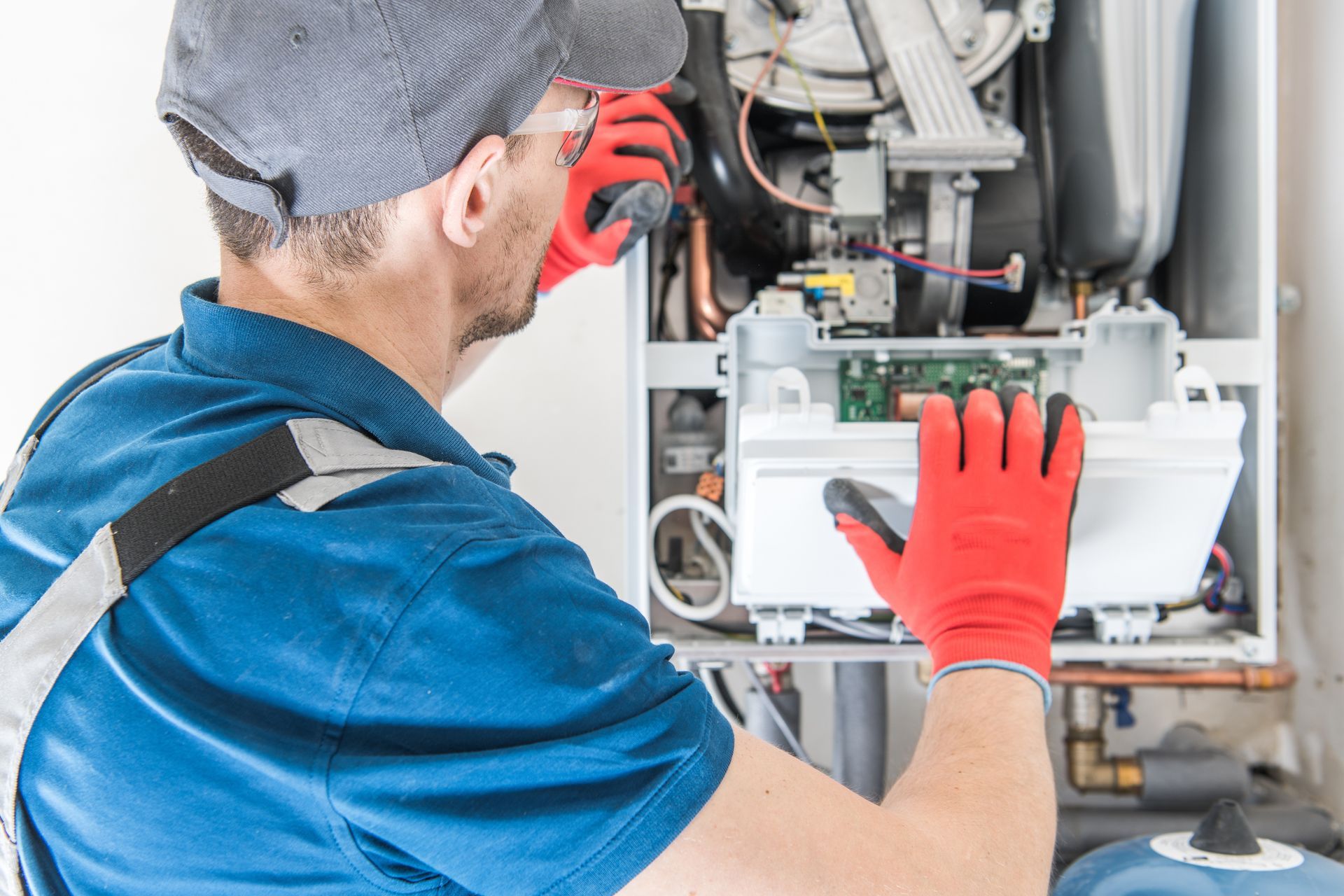 A technician checks internal components inside a residential furnace cabinet