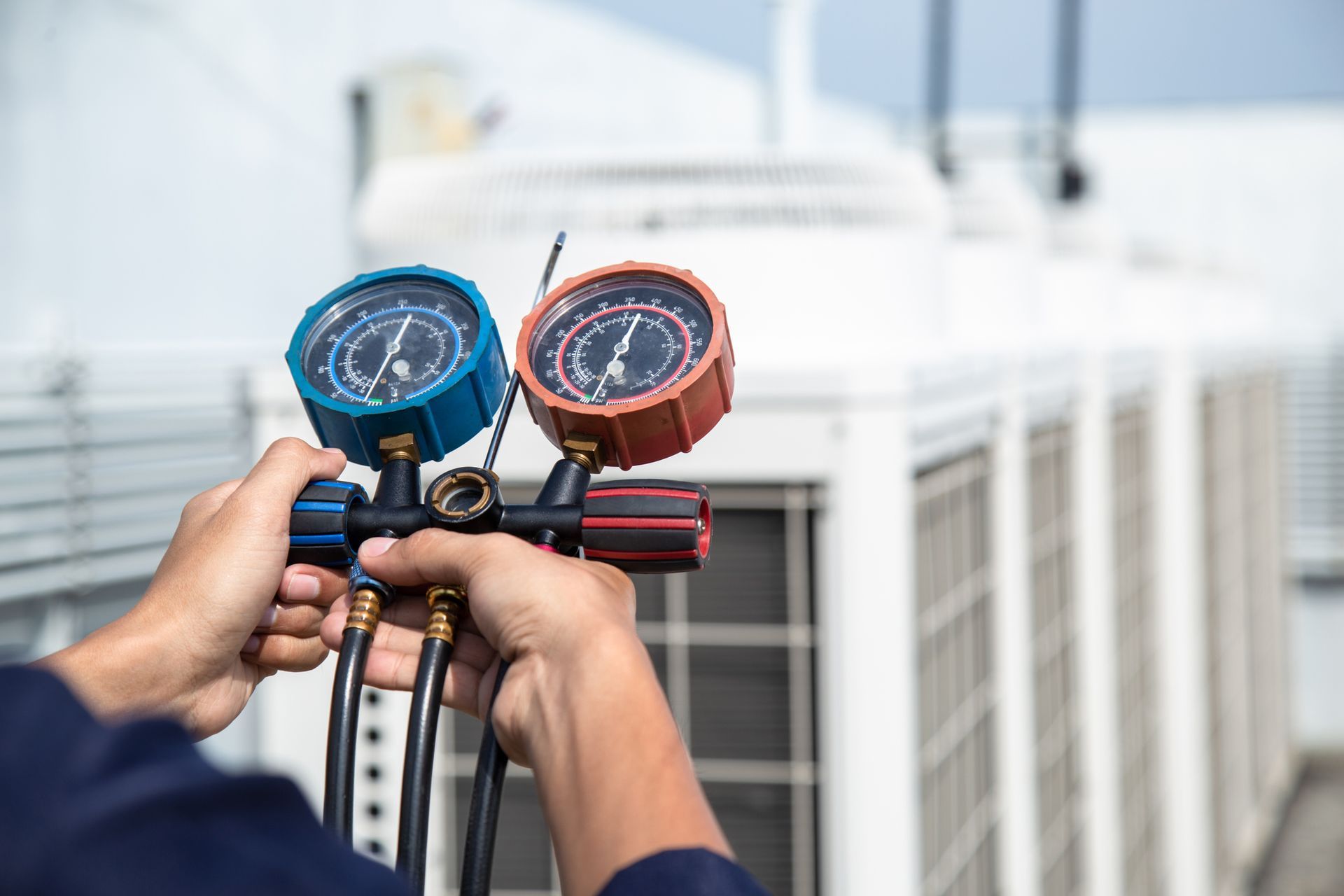Measuring Equipment — Amherst, OH — Energy 1 Heating & Air Conditioning A man is holding two gauges in front of a building.
