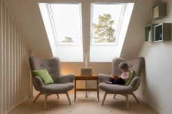 A little girl is sitting in a chair reading a book.
