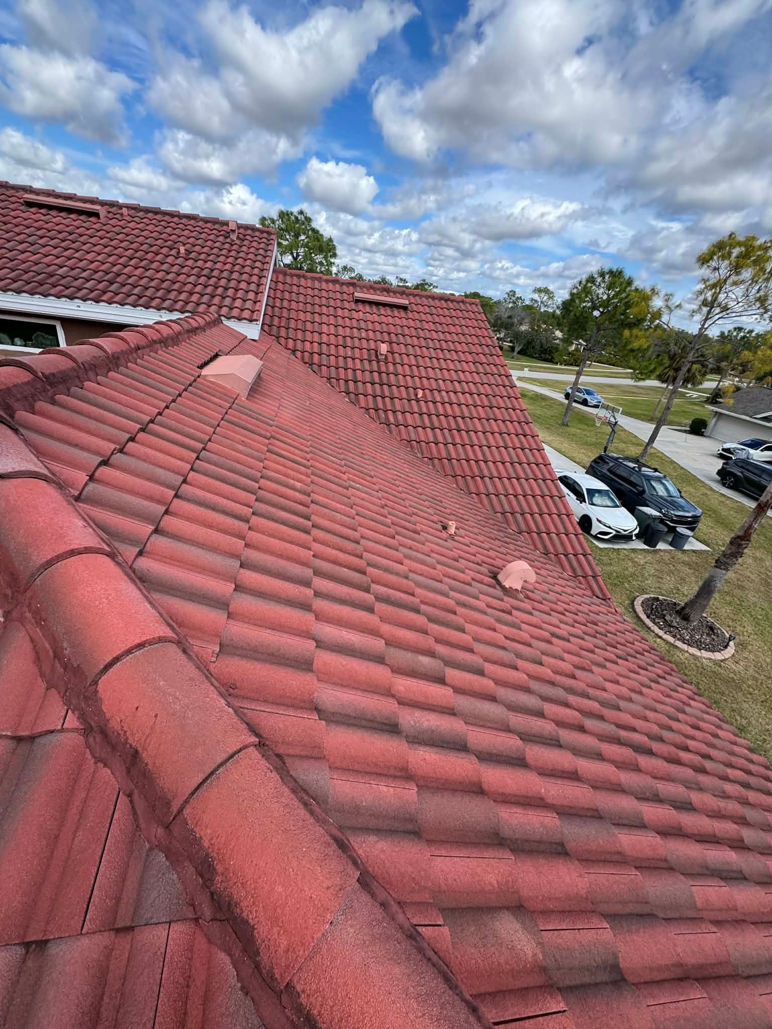 Red tiled rooftop overlooking a suburban street under a cloudy sky