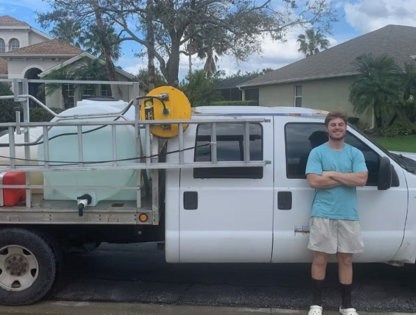 A man in a blue shirt is standing in front of a white truck
