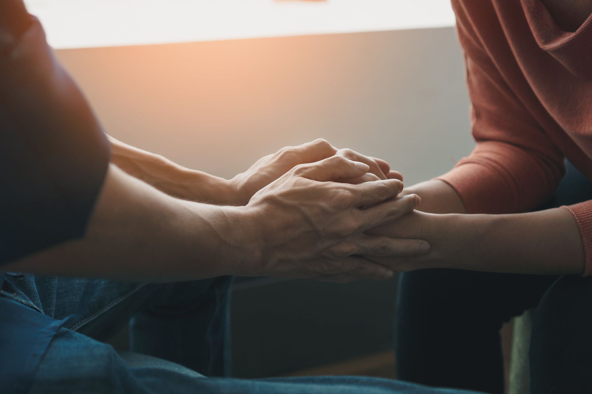 A man and a woman are holding hands while sitting next to each other.