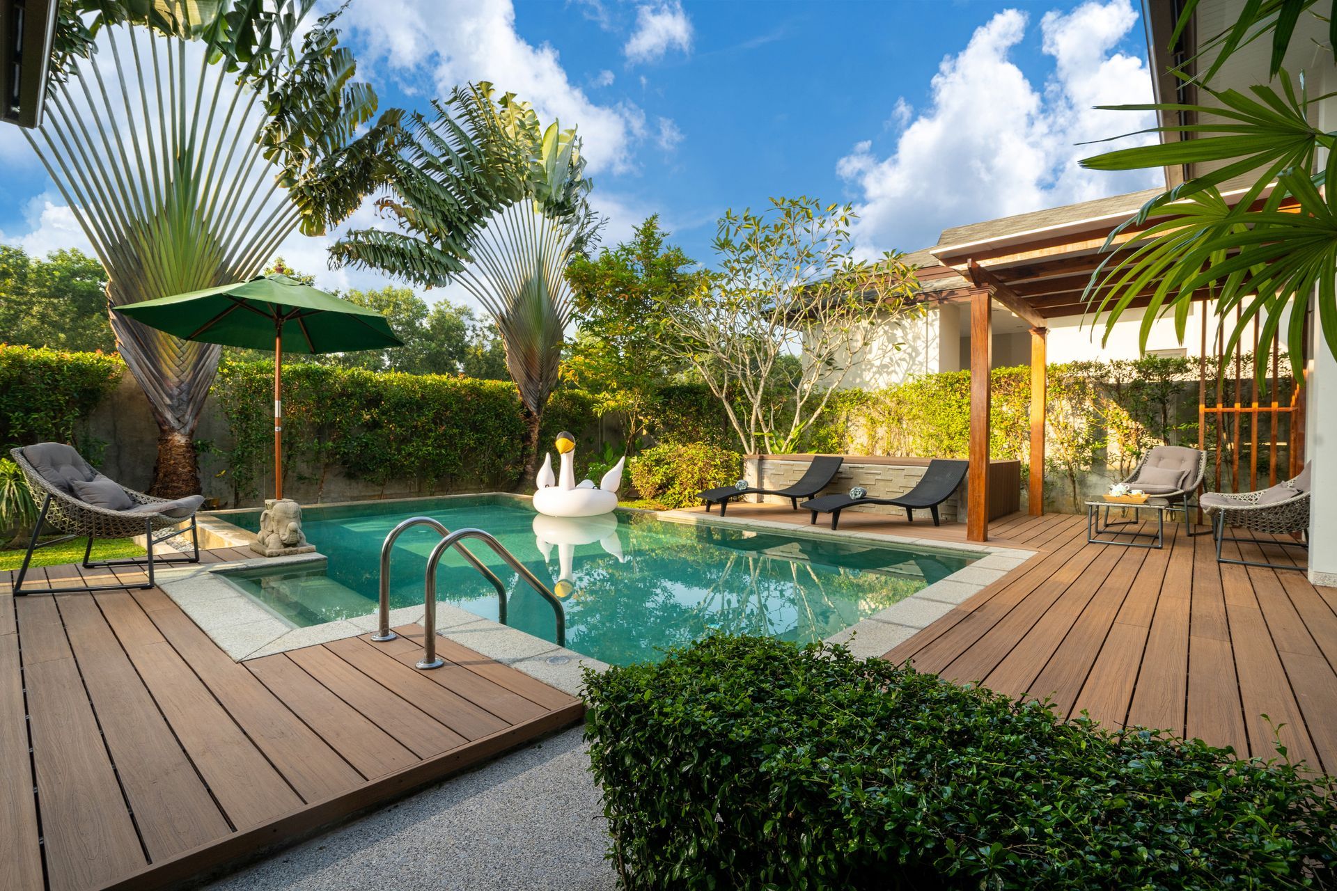 Lush garden with green lawn and colorful flower beds among palm trees