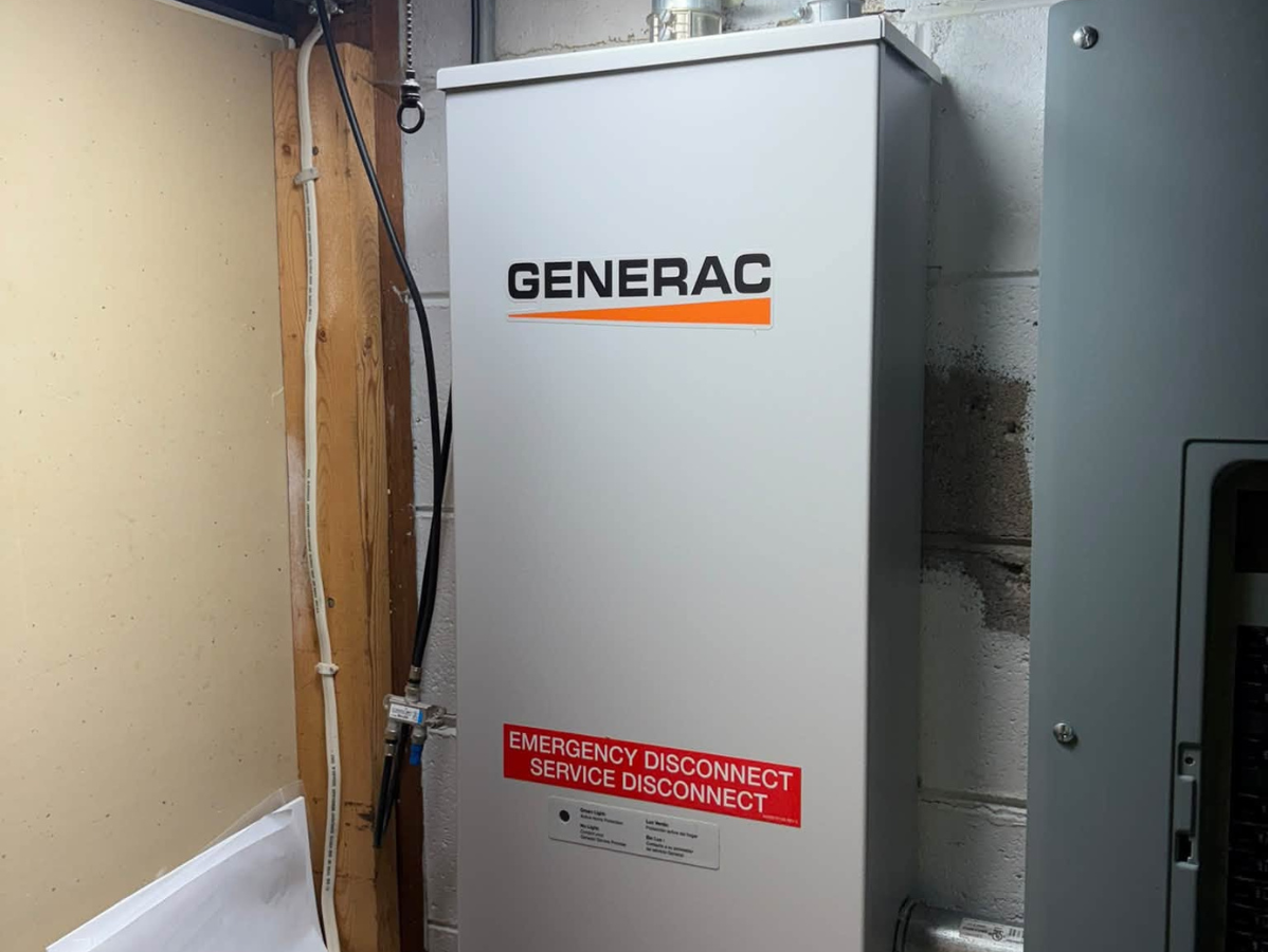Gray generator box next to several air conditioning units, in a grassy yard.