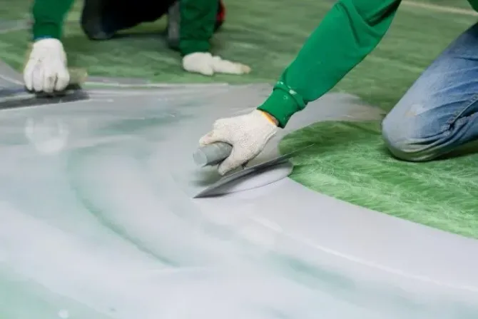 Professional installer smoothing green epoxy floor coating.