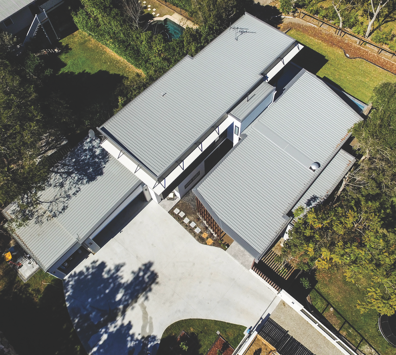 Aerial view of a house with a red roof and rooftop solar panels.