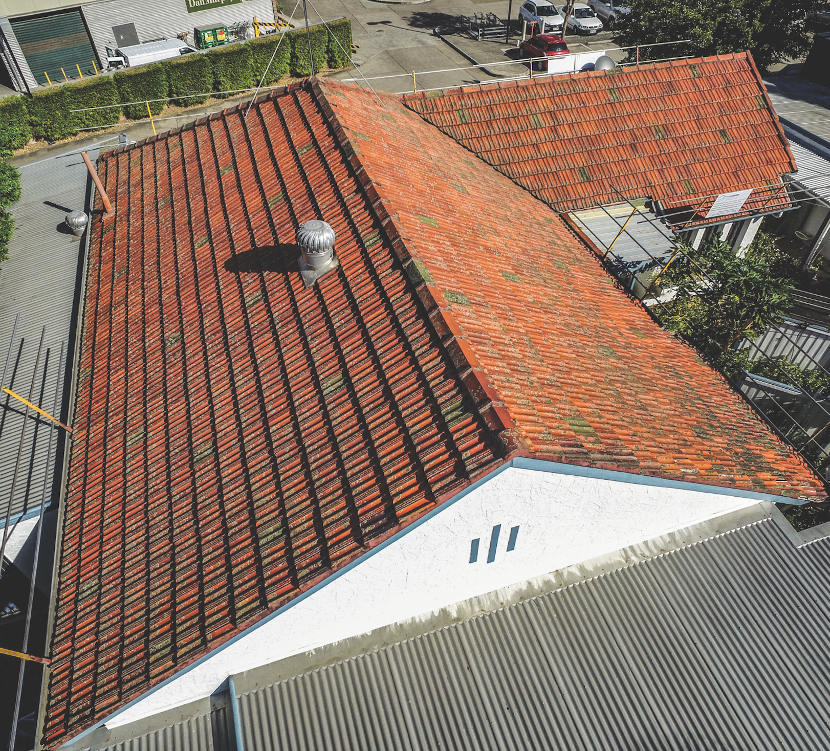 Aerial view of a building with red tiled roofs and a white gable wall.