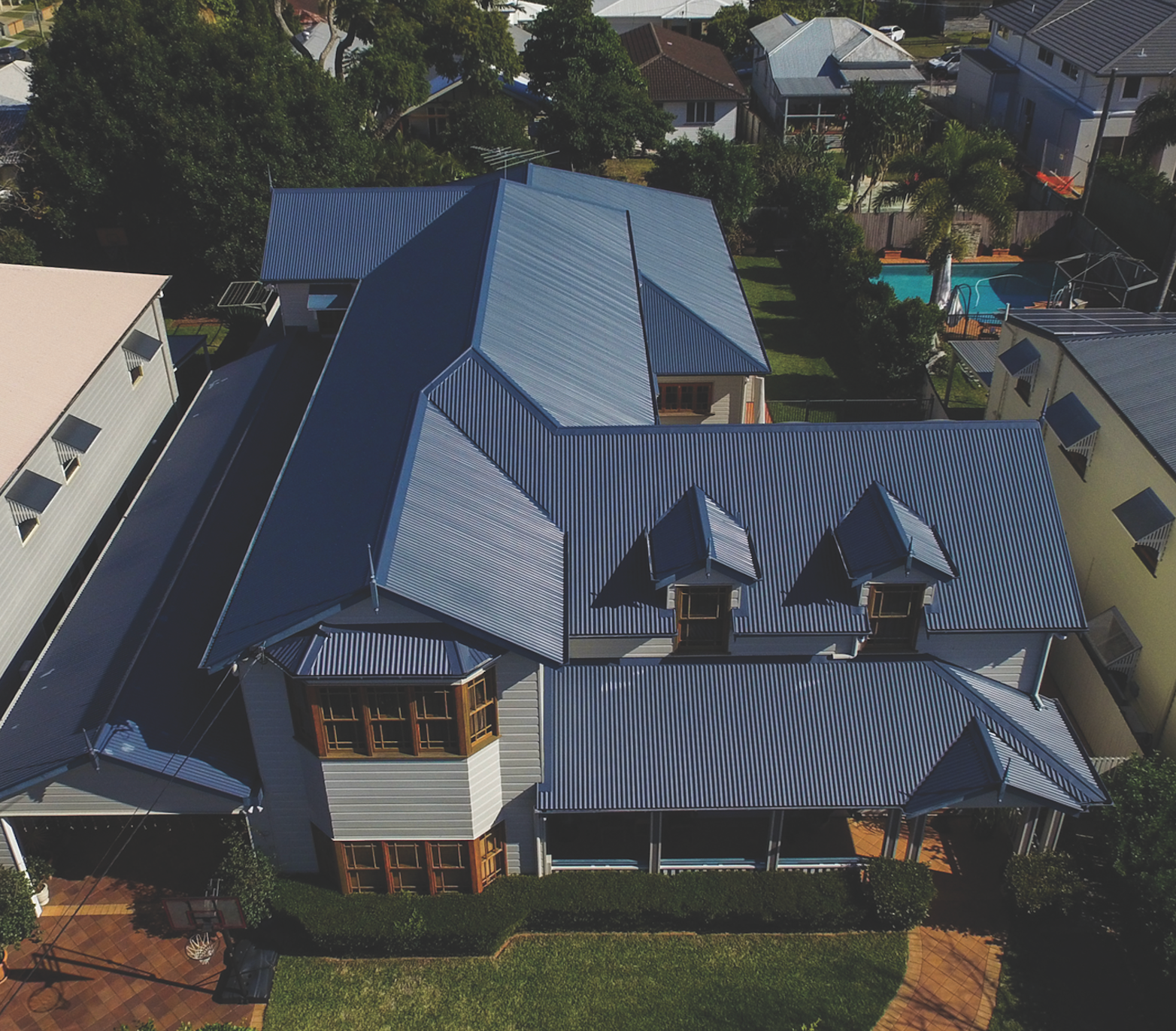 Aerial view of a house with a red roof and rooftop solar panels.
