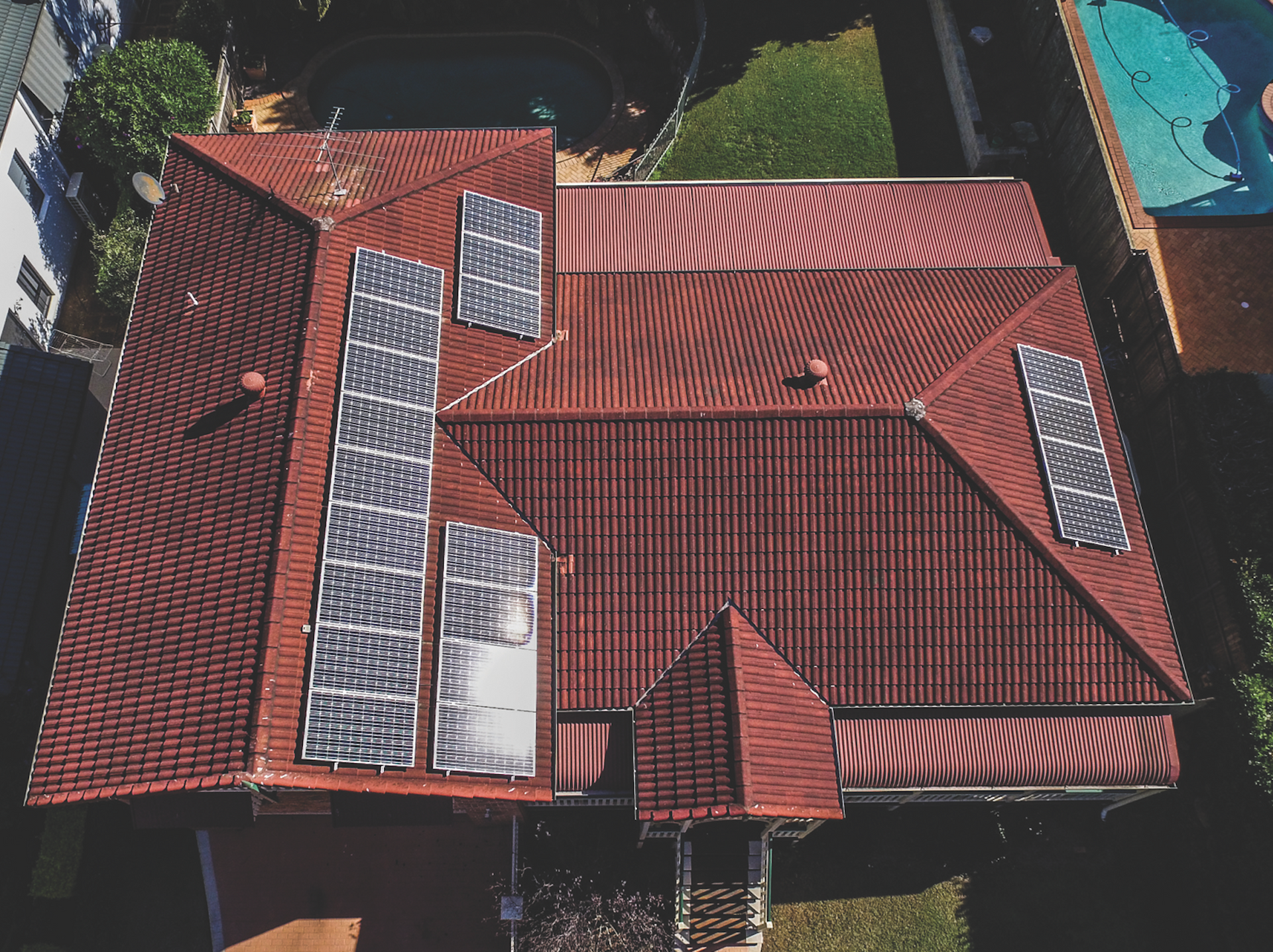 Aerial view of a red-tiled roof with several solar panels installed.