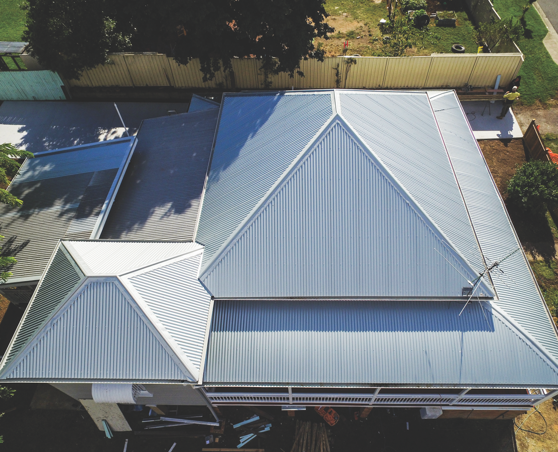 Aerial view of a house with a silver metal roof and surrounding yard fencing.