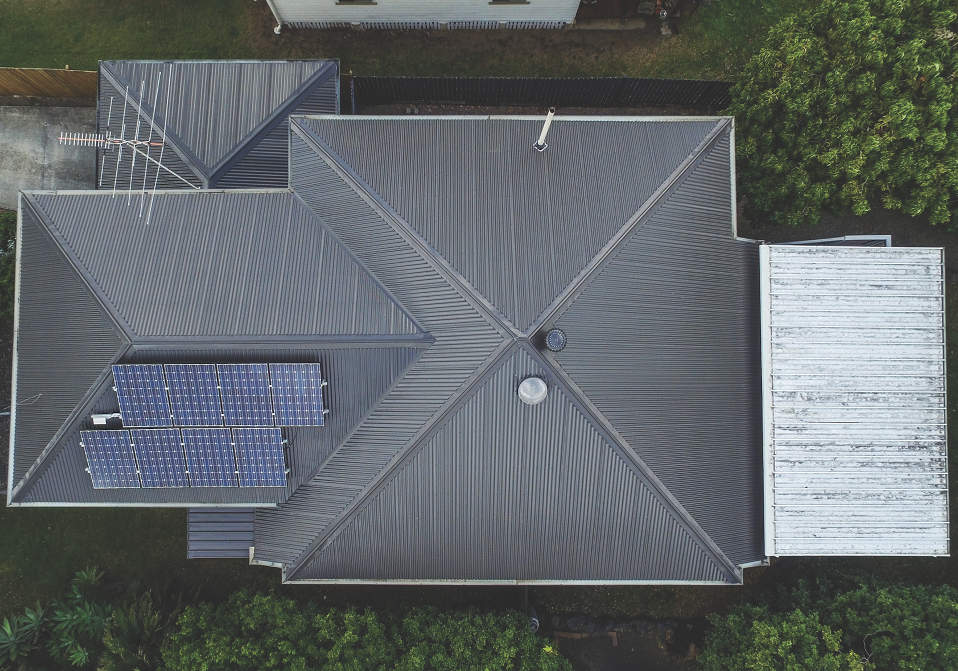 Aerial view of a house with a red roof and rooftop solar panels.