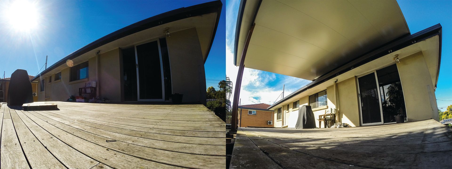 Wide-angle view of a wooden deck beside a tan building under a bright blue sky