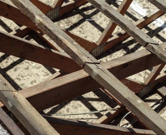 Weathered wooden beams crisscrossing over a light-colored surface, forming a grid-like pattern