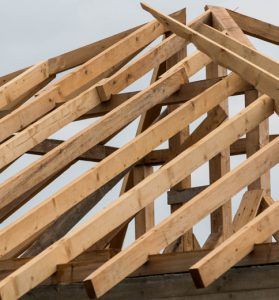 Wooden roof trusses under construction against a clear sky