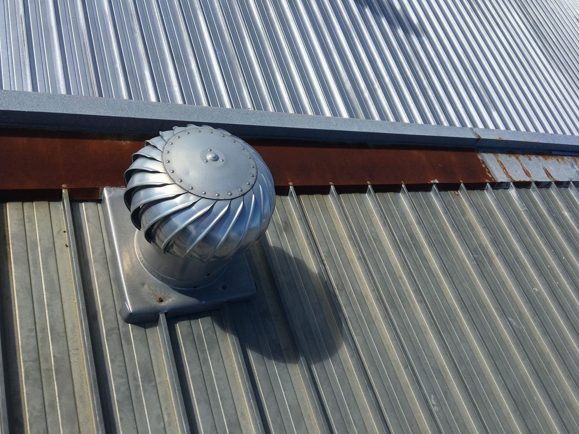 Silver roof turbine vent on a corrugated metal rooftop