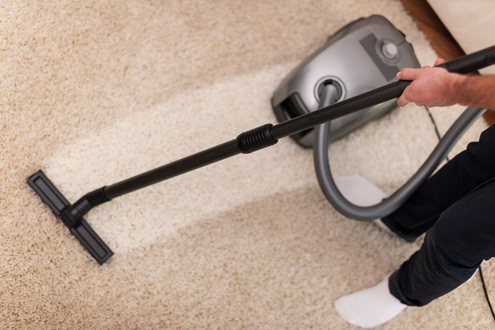 Vacuum cleaner cleaning a beige carpet, removing dirt, leaving a clean path.