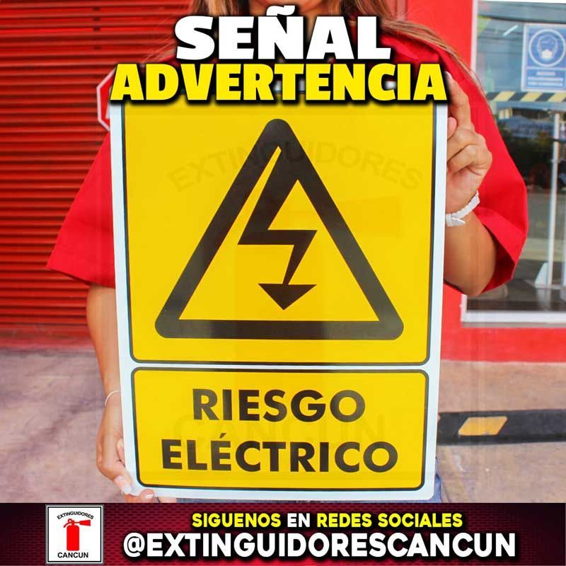 Una mujer sostiene un cartel que dice riesgo eléctrico.