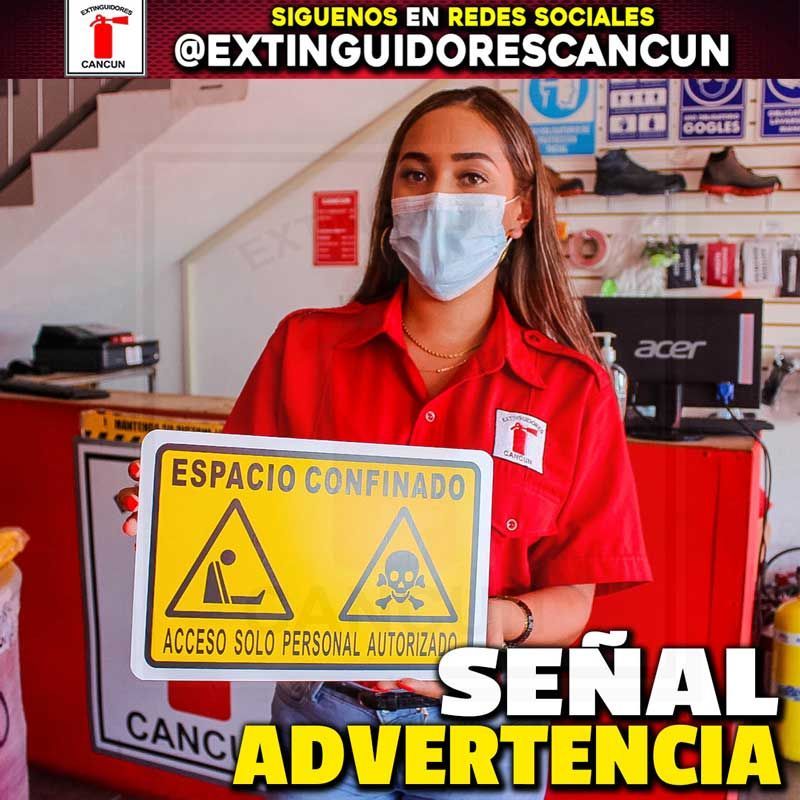 Una mujer con mascarilla sostiene un cartel que dice espacio confinado.