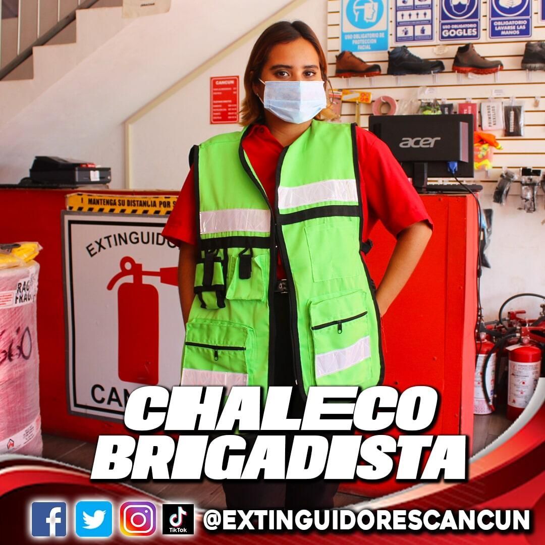 Una mujer con una máscara y un chaleco verde con las palabras chaleco brigadista.