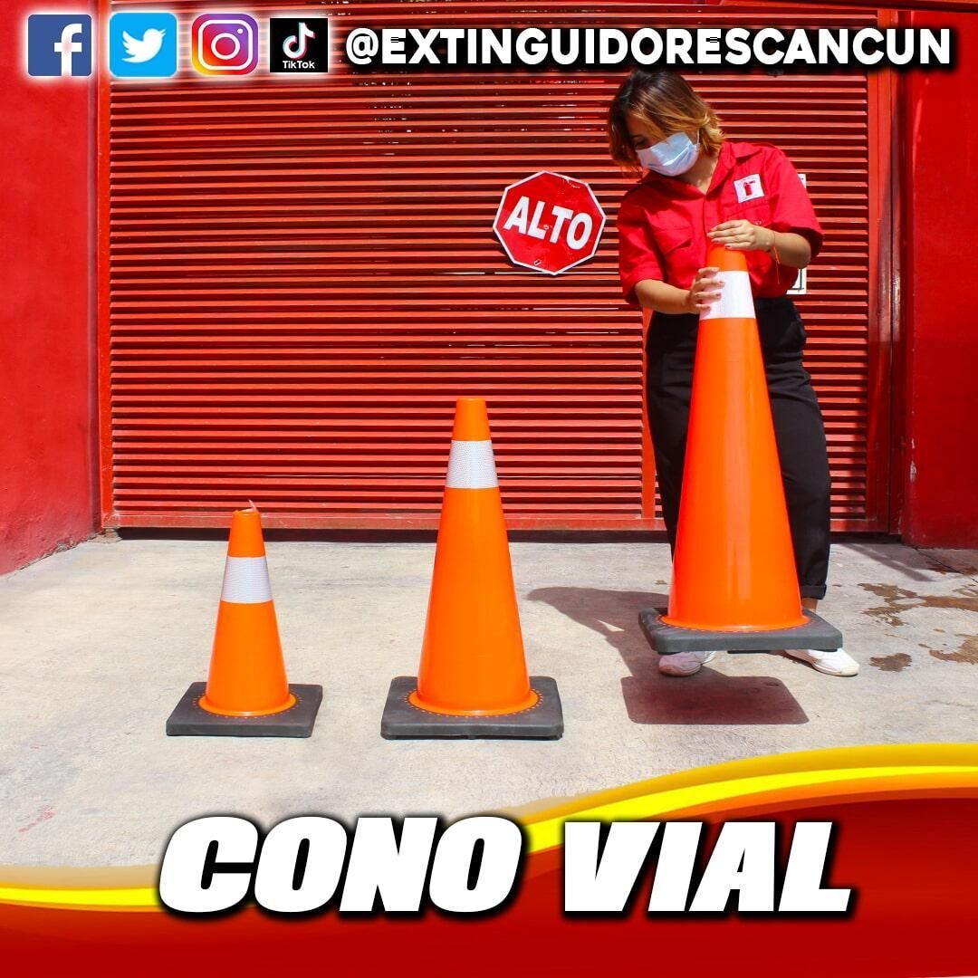 Una mujer con máscara está parada junto a tres conos de tráfico de color naranja.