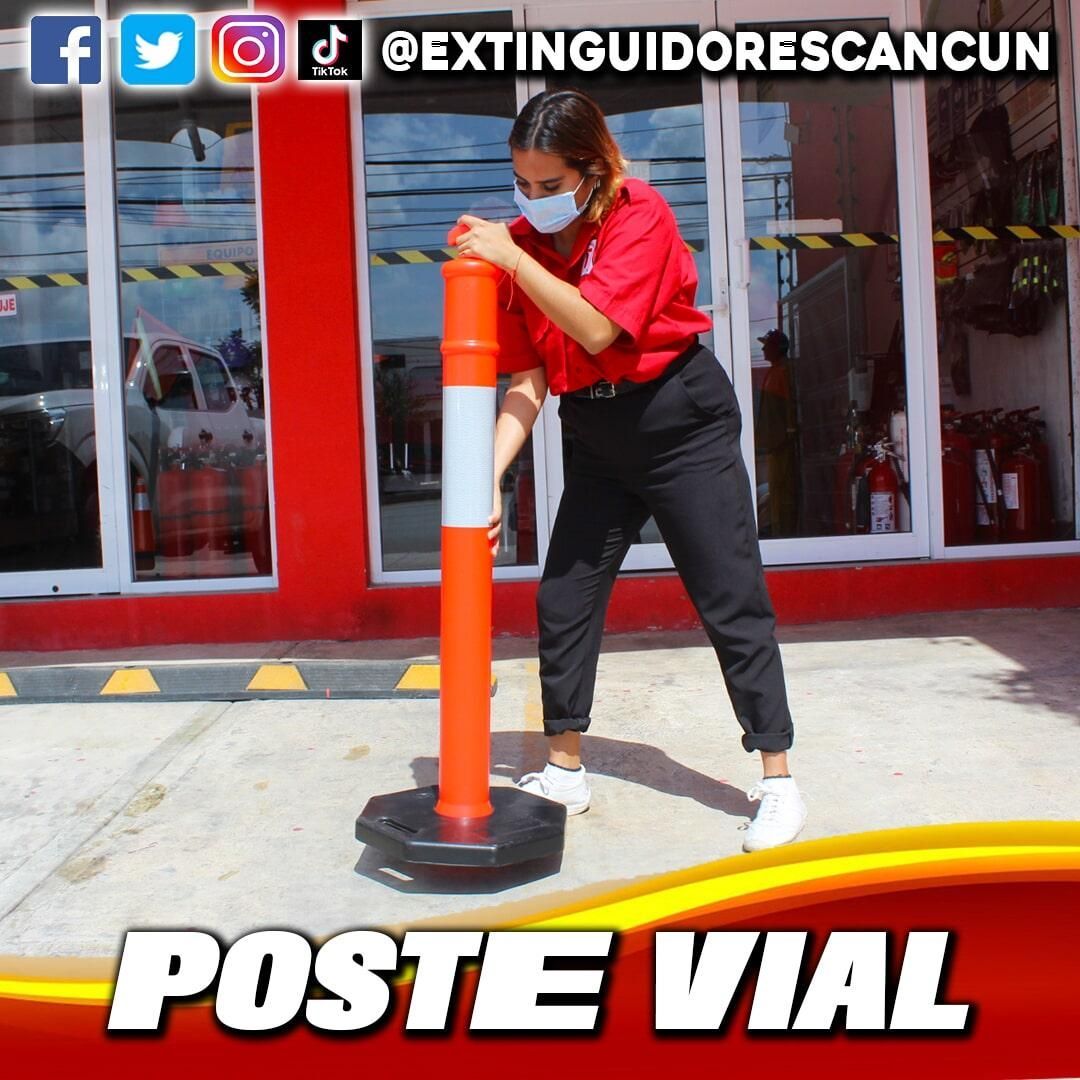 Una mujer con mascarilla está parada junto a un poste naranja que dice poste vial.